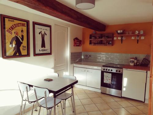 una cucina con tavolo e sedie e un fornello di La Maison D'amis a Souesmes