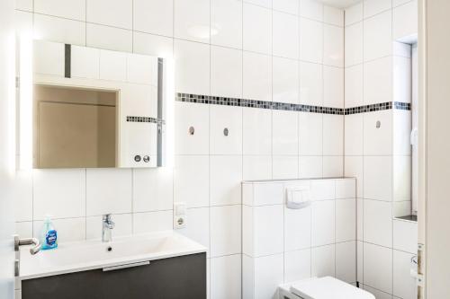 a white bathroom with a sink and a toilet at Ferienwohnung Hilbers in Horumersiel