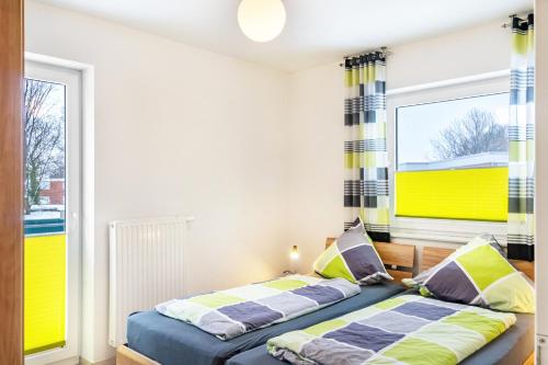 a bedroom with two beds and two windows at Ferienwohnung Hilbers in Horumersiel