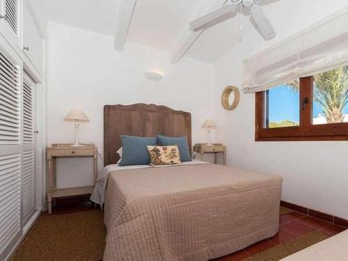 a bedroom with a bed with blue pillows and a window at Villa Rocío in Binibeca