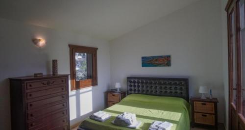 a bedroom with a green bed and a dresser at Villetta Vittoria in Macari