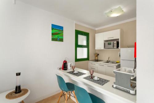 a kitchen with a white counter and blue chairs at Casa Orballo in Mogán