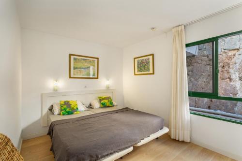 a white bedroom with a bed and a window at Casa Orballo in Mogán
