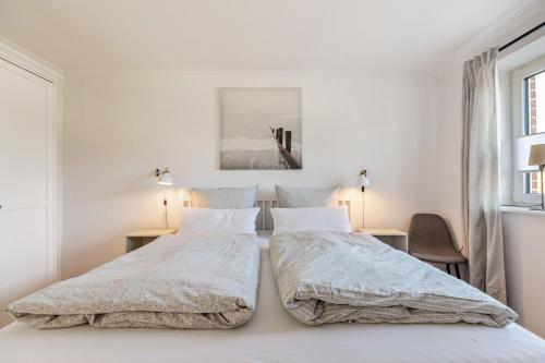 two beds in a bedroom with white walls at Ferienhaus Waterkant mit Hund in Klanxbüll