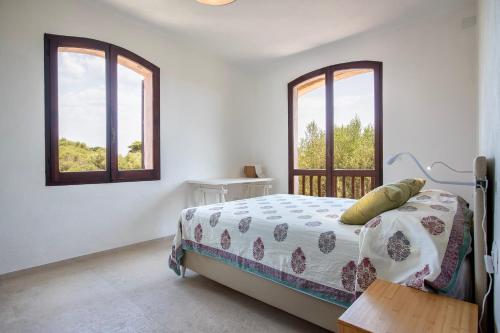 a bedroom with a bed and two windows at Villa Grecale in Stintino