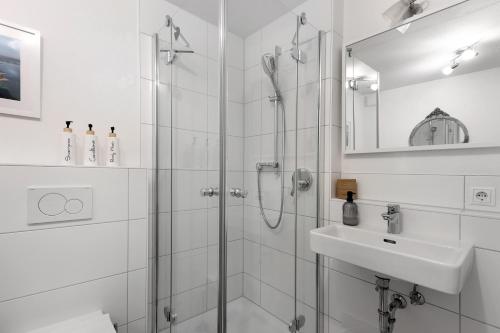 a white bathroom with a shower and a sink at Ferienwohnung Im Laubgarten in Öhningen