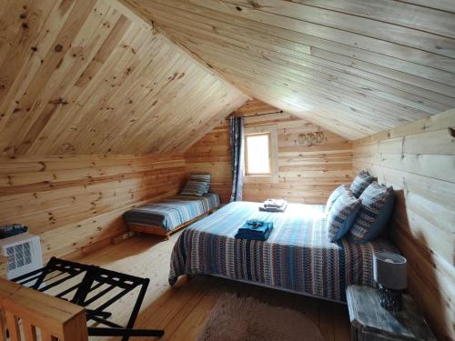 a bedroom in a log cabin with a bed and a couch at Au chant des oiseaux - rouge gorge in Varen