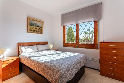 a bedroom with a bed and a dresser and a window at Durero in Pineda de Mar