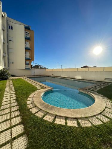 a swimming pool in the grass next to a building at Onda Beach House in Cortegaça