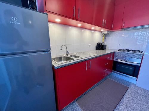 a red kitchen with a sink and a refrigerator at Onda Beach House in Cortegaça