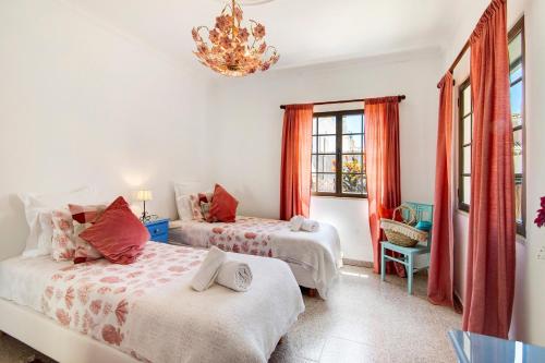 a bedroom with two beds and a chandelier at Sunshine House in Faro