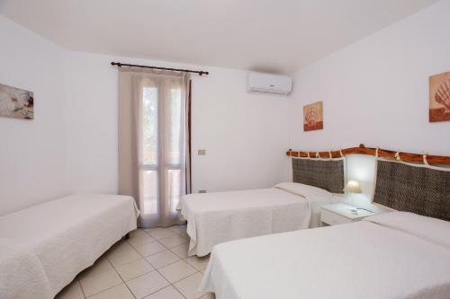 a white room with two beds and a window at mirtagru casa della Sughereta in Budoni