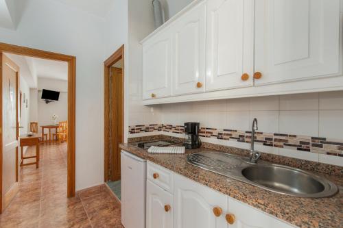 a kitchen with white cabinets and a sink at Apartamentos Martin - 22 in Puerto Naos