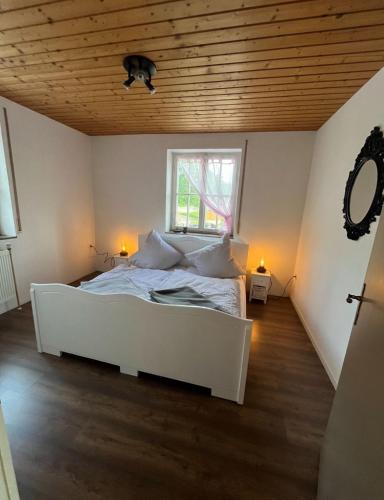 a bedroom with a white bed and a window at Ferienwohnung Modelshauser Mühle in Hinterbuch