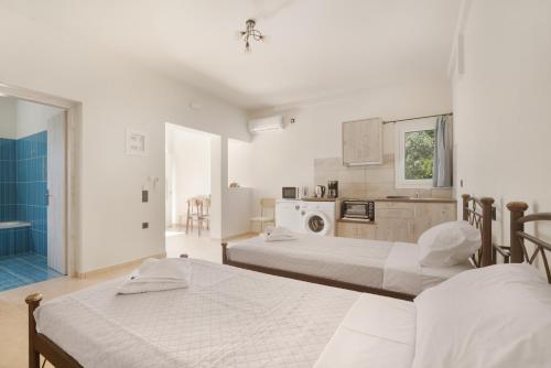 a white room with two beds and a kitchen at Panagis Apartments in Argostoli