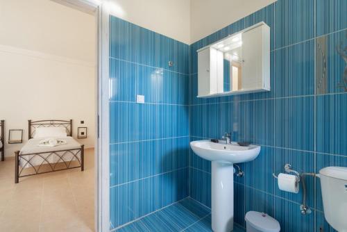 a blue tiled bathroom with a sink and a toilet at Panagis Apartments in Argostoli