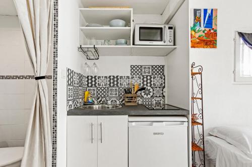 a small kitchen with a sink and a microwave at Appartement Pinède Romane Fréjus in Fréjus