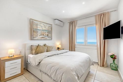 a white bedroom with a bed and a television at Adriana in Denia