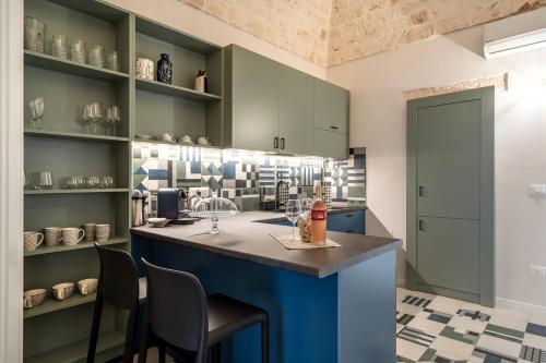 a kitchen with green cabinets and a blue island with chairs at Civico40 Suite in Locorotondo