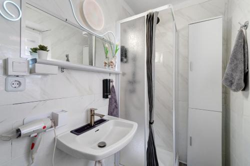 a white bathroom with a sink and a shower at Museum View, vista sul museo in Sassello
