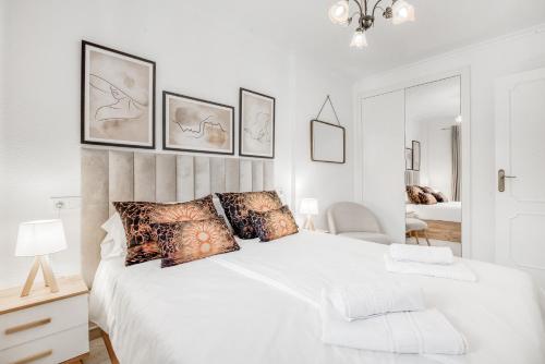 a white bedroom with a large white bed with pillows at Verano Azul in La Mata