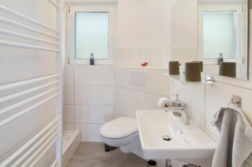 a white bathroom with a toilet and a sink at Smolly's Ferienwohnung in Bad Zwischenahn