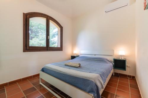 a bedroom with a bed with a mirror and a window at Villa Ulivi 10 in Is Molas 