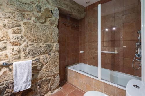 a bathroom with a stone wall and a bath tub at Lugar Da Xacra in Meder