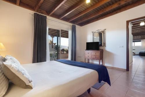 a bedroom with a large bed and a television at Almar in Tinajo