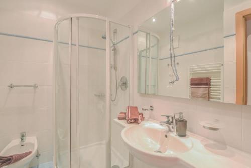 a white bathroom with a shower and a sink at Apartments Christa App B2 in Ortisei