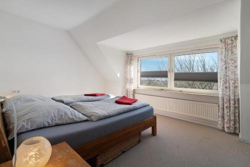ein Schlafzimmer mit einem Bett und einem Fenster in der Unterkunft Waldhusenwarft in Pellworm