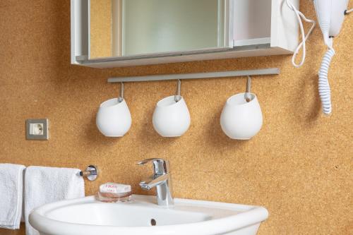 a bathroom with a sink and three mugs on the wall at Studio Colline di Bardolino in Bardolino