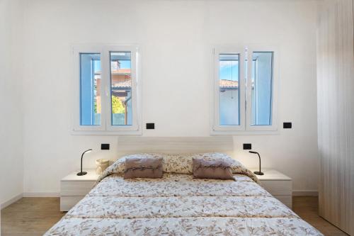a bedroom with a bed with two windows at Villa Lilia in Arona