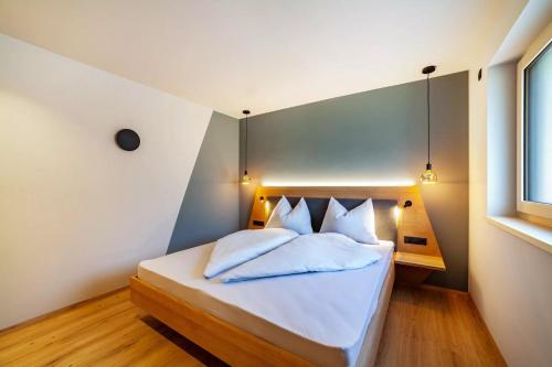 a bedroom with a bed with white sheets and pillows at Aktiv Lodge Meran - Terrace One in San Martino