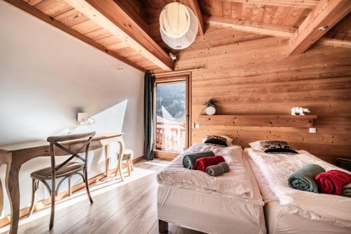 two beds in a wooden room with a desk at Chalet Heidi - Chatel in Châtel