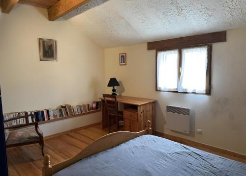 a bedroom with a bed and a desk and a window at Gite Chez Lucien in Trébas