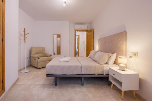 a bedroom with a large bed and a chair at Apartamento Molinillo in Monachil