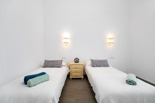 two twin beds in a room with white walls at Piso con Encanto in Cádiz