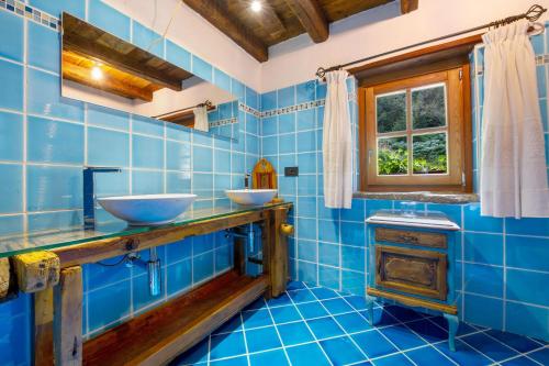 a blue tiled bathroom with two sinks and a window at Le Chalet du Coq Rouge in Valtournenche