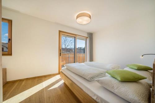 a white bedroom with a large bed with green pillows at sunnig Apartment Sonnenaufgang in Vollan