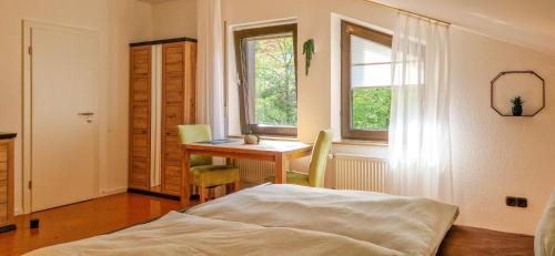 a bedroom with a bed and a desk and a window at Fewo Jörges in Obernhausen