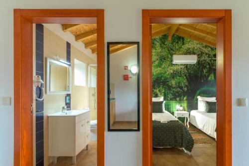 a bathroom with a mirror and a bedroom with a bed at Herdade Vale de Gaios in Odemira