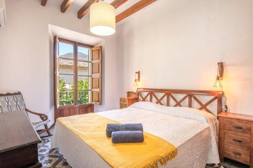 a bedroom with a bed and a chair and a window at Casa Tramuntana in Sóller