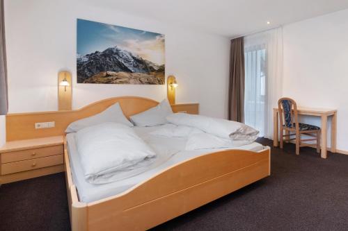a bedroom with a bed with a desk and a chair at Haus Lena in Solda