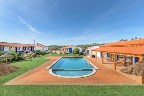 a swimming pool in a yard next to a house at Herdade Vale de Gaios in Odemira