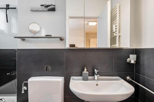 a bathroom with a sink and a toilet and a mirror at Schwarzwaldblick K App 4 mit Pool in Schönwald
