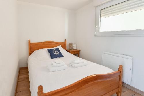 a bedroom with a bed with white sheets and a window at La Madély in Camiers