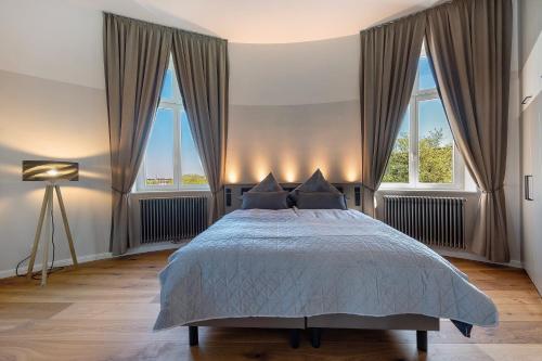 ein Schlafzimmer mit einem großen Bett und zwei Fenstern in der Unterkunft Café Wasserturm Cuxhaven in Cuxhaven