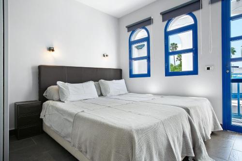 a bedroom with a large bed with blue windows at Playmar6970 in Maspalomas