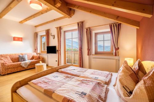 ein Zimmer mit einem Bett, einer Couch und Fenstern in der Unterkunft Oberplunerhof - Fewo Kronplatz in Kiens